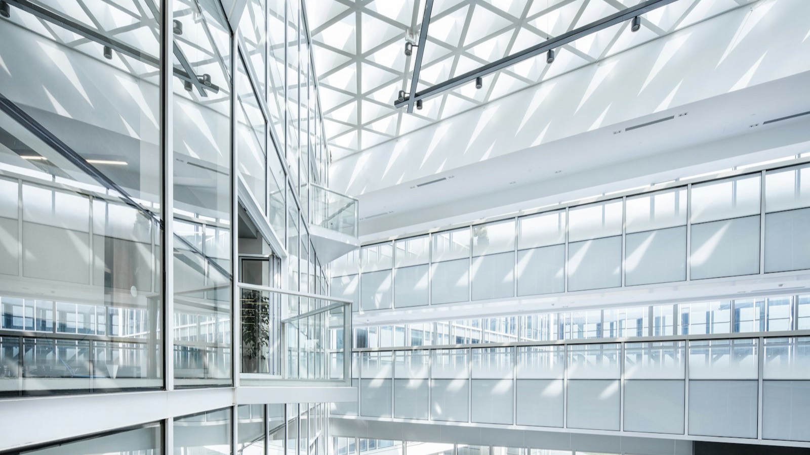 The glass interior of a modern office building in daylight.
