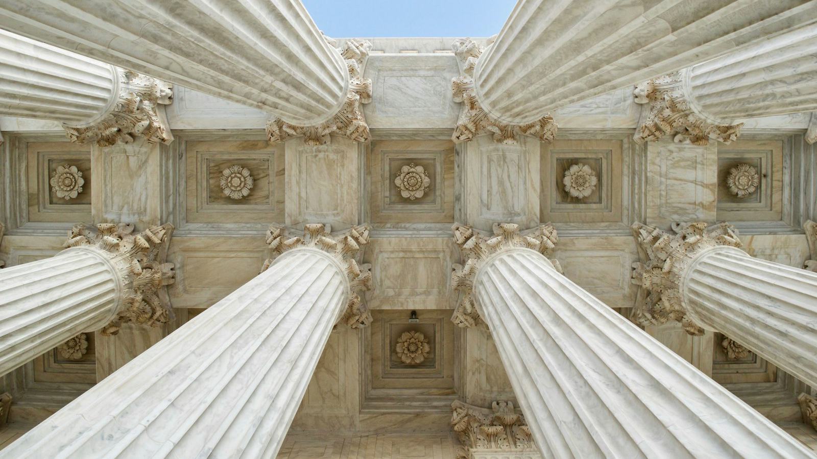 Stone columns of a courthouse seen from below.