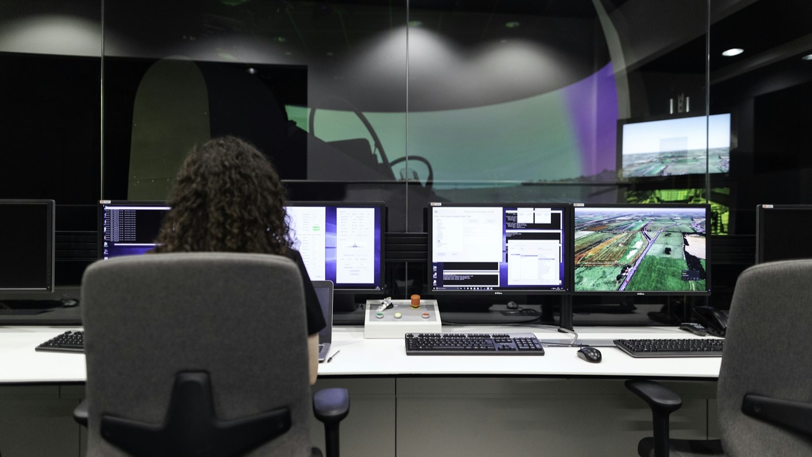 An operator works before a wall of monitors in a dispatch control room.